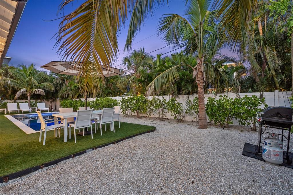 305 73rd Street Holmes Beach, FL 34217 - Photo 17 of 59 a view of a backyard with a table and chairs under palm trees