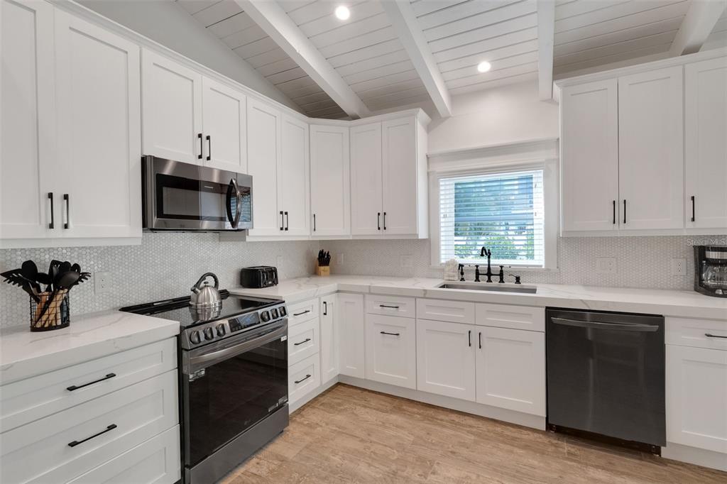305 73rd Street Holmes Beach, FL 34217 - Photo 40 of 59 a kitchen with white cabinets and black appliances