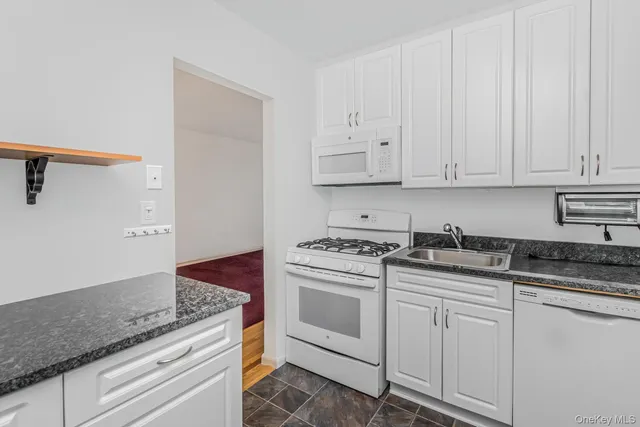 a kitchen with granite countertop white cabinets and white appliances
