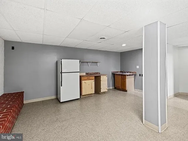 a view of kitchen with refrigerator and white cabinets