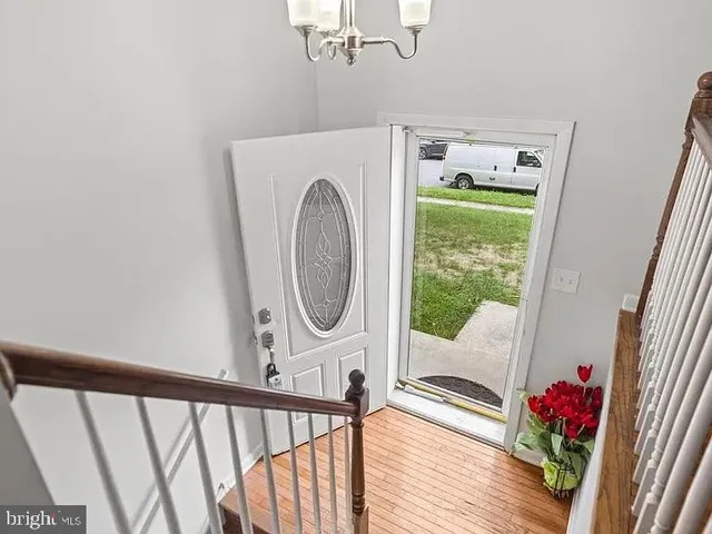 a view of a hallway with wooden floor and a chandelier