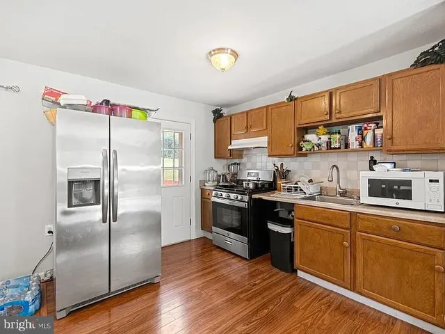 a kitchen with stainless steel appliances granite countertop a refrigerator a sink dishwasher a stove with wooden cabinets and floor