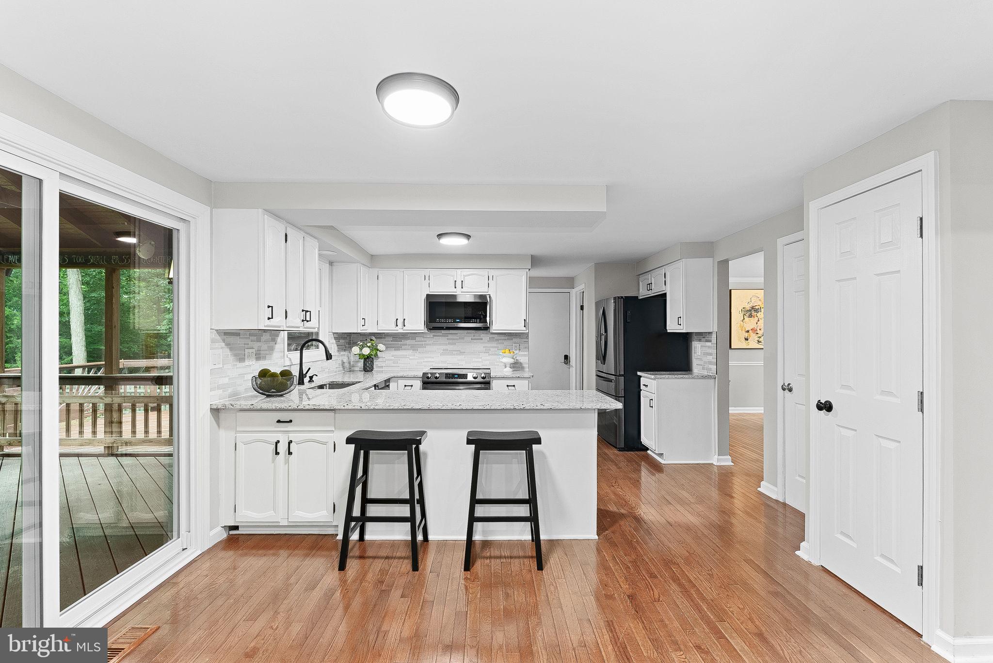 128 Applegate Drive Sterling, VA 20164 - Photo 18 of 58 a kitchen with stainless steel appliances a stove a refrigerator a sink dishwasher and a dining table with wooden floor
