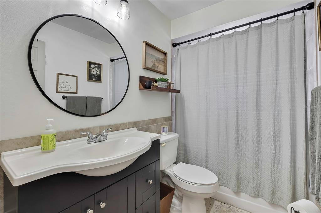 14154 Trollman Street Spring Hill, FL 34609 - Photo 17 of 25 a bathroom with a sink a mirror a toilet and a window