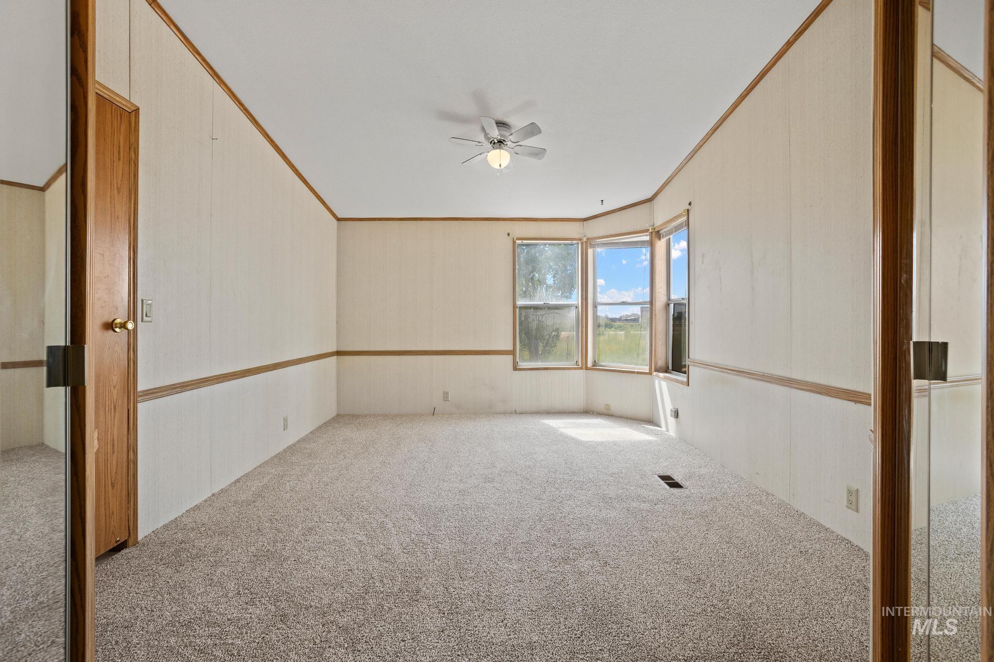 3680 South Mill Road Emmett, ID 83617 - Photo 28 of 38 Spacious room featuring light-colored carpeting, white paneled walls with wood trim, and a ceiling fan
