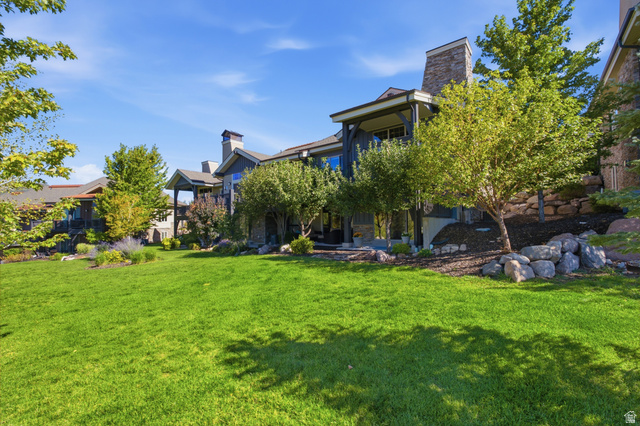 5207 North Oldgate Road Heber City, UT 84032 - Photo 43 of 58 Expansive green lawn with mature trees and landscaped rock retaining walls, complementing the property's exterior