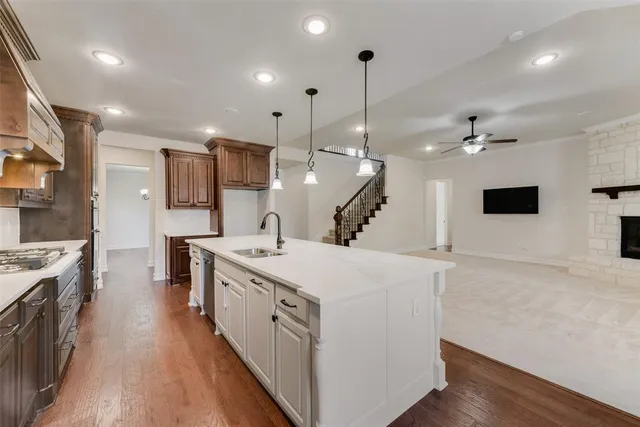 a large kitchen with stainless steel appliances kitchen island a large counter top a stove a chimney a sink and a living room view