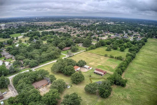 an aerial view of residential houses with outdoor space and trees