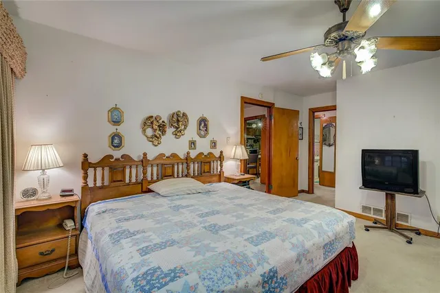 a bedroom with a bed and a flat tv screen on dresser