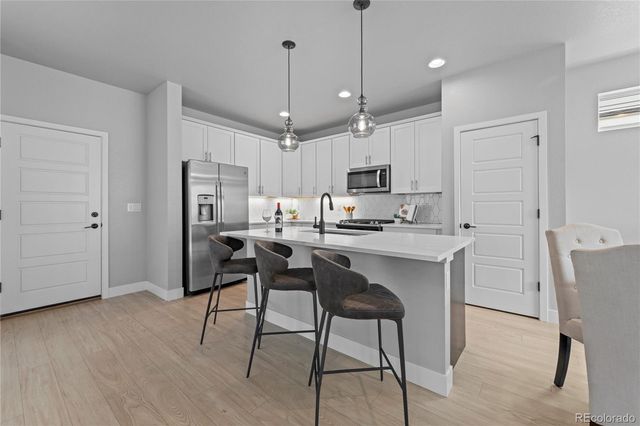 a kitchen with kitchen island white cabinets and stainless steel appliances