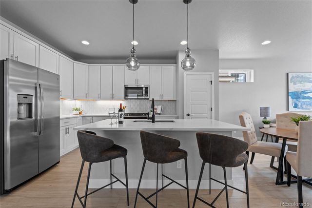 a kitchen with stainless steel appliances granite countertop a sink a stove a refrigerator cabinets and chairs