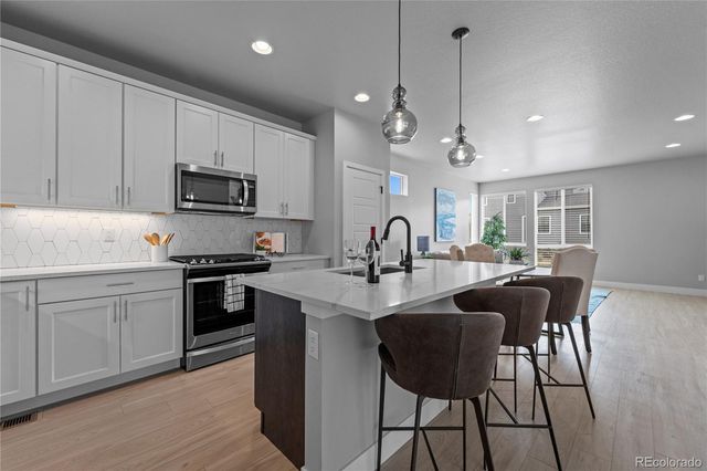 a kitchen with stainless steel appliances granite countertop a sink a stove a refrigerator cabinets and chairs