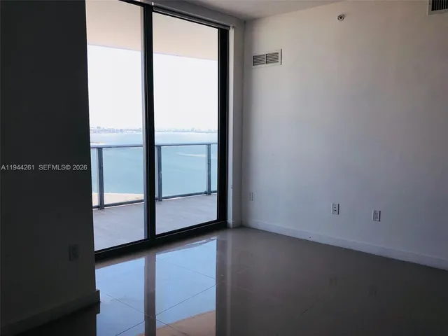 a view of an empty room with wooden floor and windows