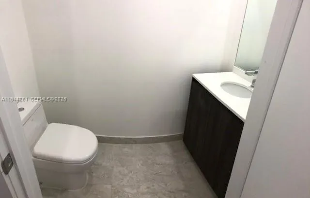 a white toilet sitting next to a white sink and vanity