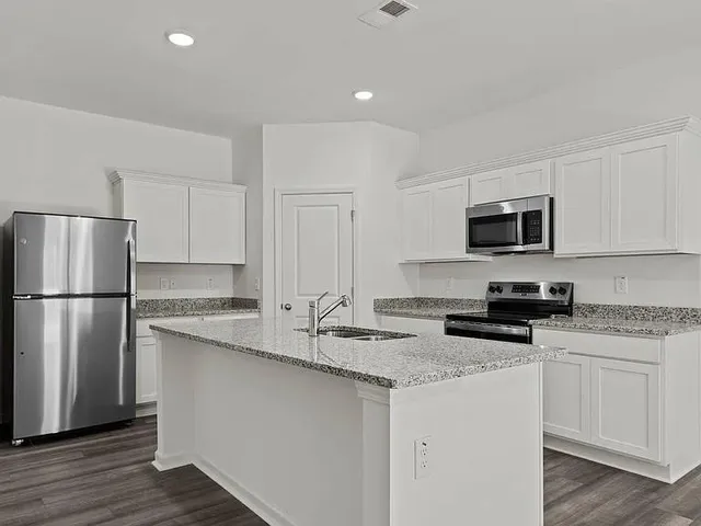 a kitchen with a sink a refrigerator a microwave and cabinets