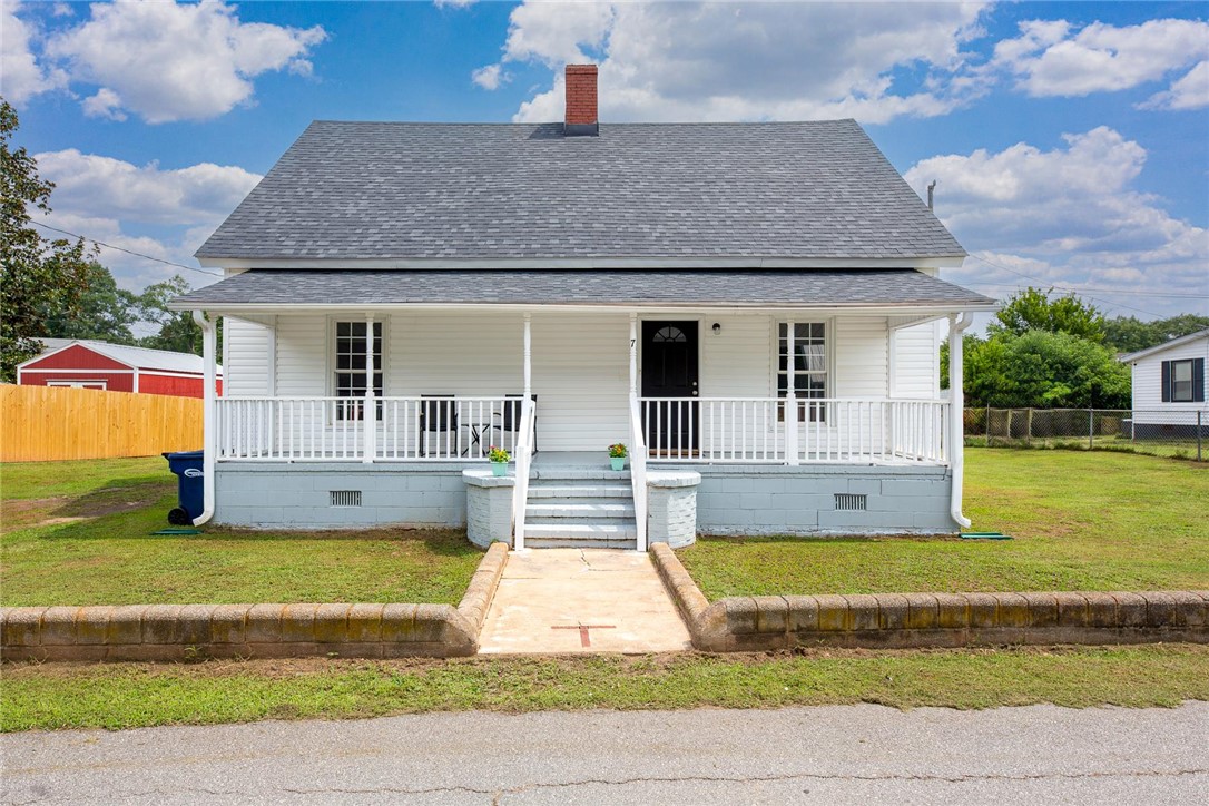 7 McCaughrin Street Pelzer, SC 29669 - Photo 2 of 24 A welcoming front porch with white railings graces this classic single-story residence.