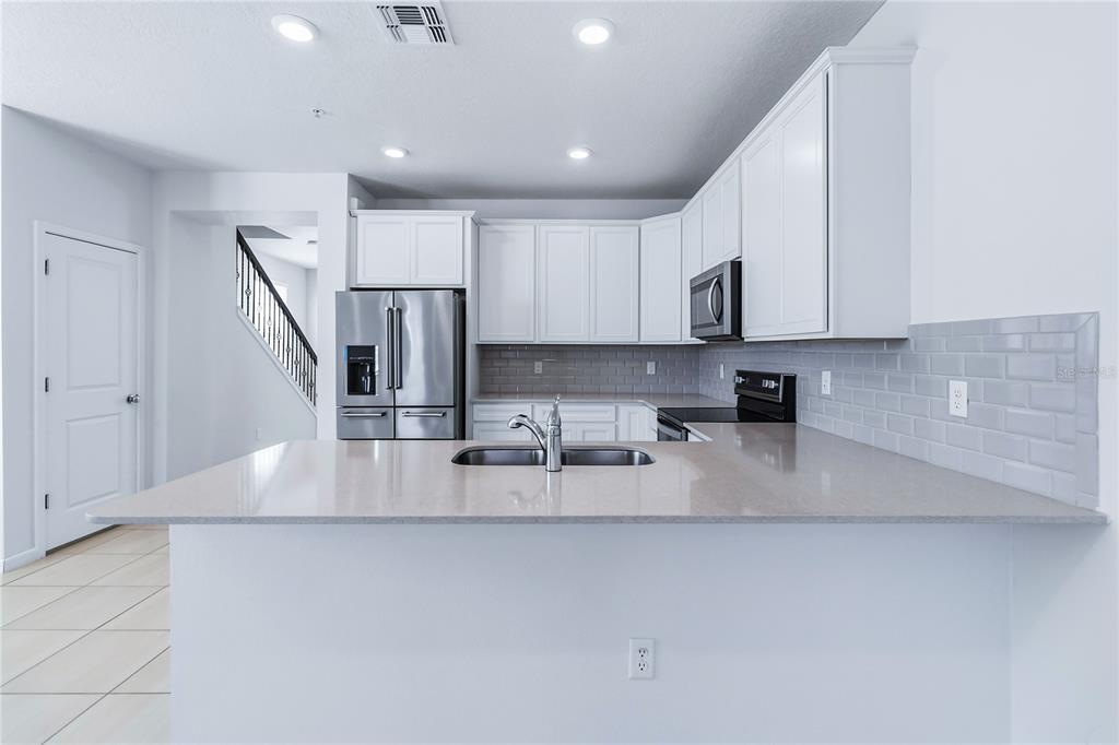 10379 Folly Beach Road Orlando, FL 32827 - Photo 17 of 54 a kitchen with stainless steel appliances granite countertop a sink a stove and a refrigerator