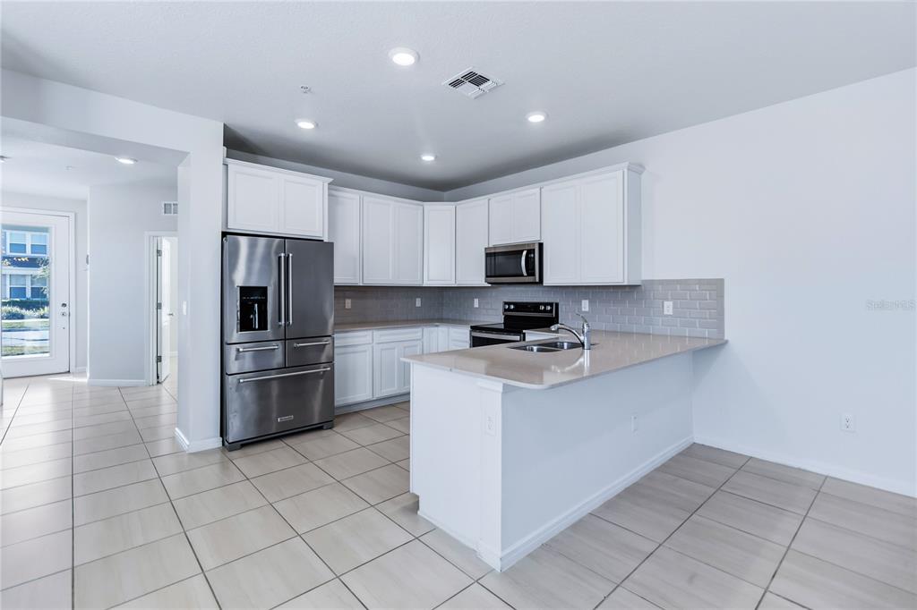 10379 Folly Beach Road Orlando, FL 32827 - Photo 21 of 56 a kitchen with stainless steel appliances a refrigerator stove microwave and cabinets