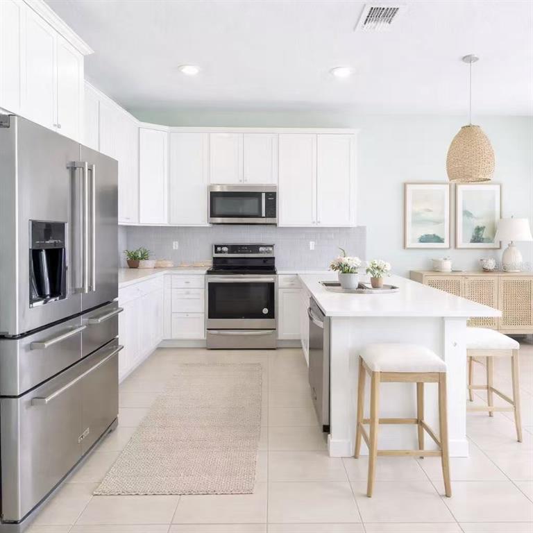 10379 Folly Beach Road Orlando, FL 32827 - Photo 3 of 54 a kitchen with stainless steel appliances a stove a sink a microwave a refrigerator and cabinets