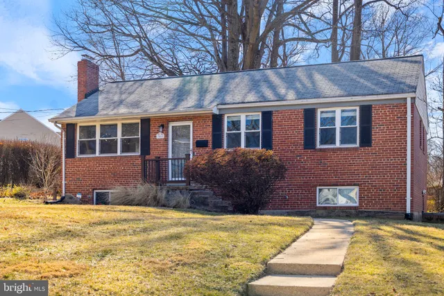 a front view of a house with a yard and large tree