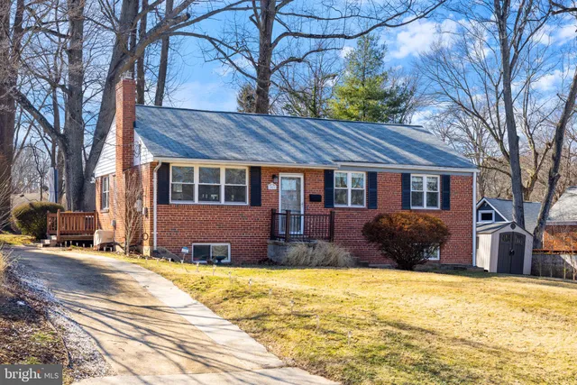 a front view of a house with a yard covered with snow and trees