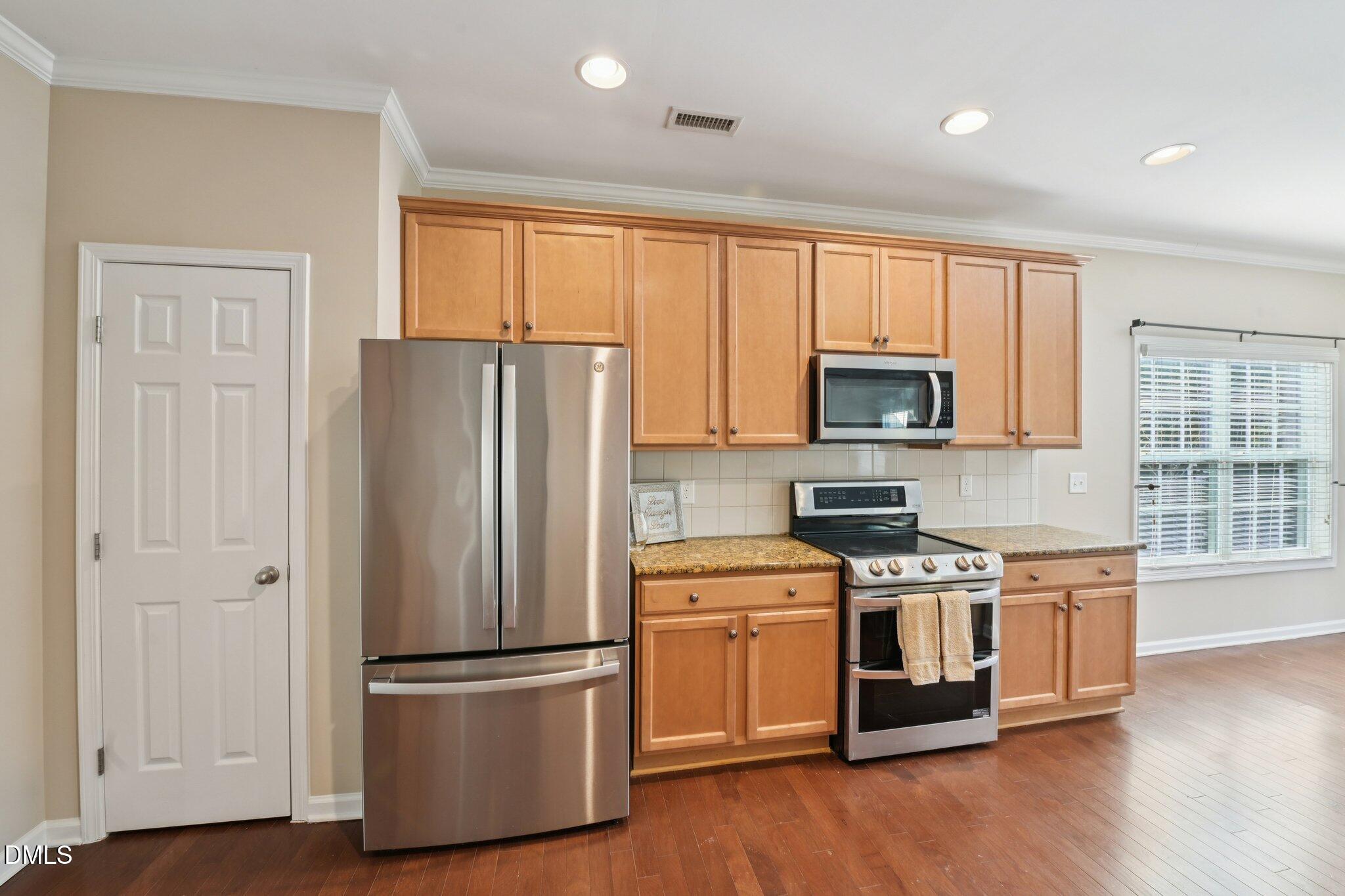 11 Hidden Ridge Court Durham, NC 27707 - Photo 9 of 30 a kitchen with stainless steel appliances a refrigerator and wooden floor