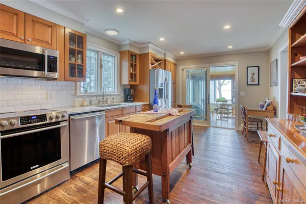 a kitchen with stainless steel appliances granite countertop a stove a sink dishwasher a dining table and chairs with wooden floor