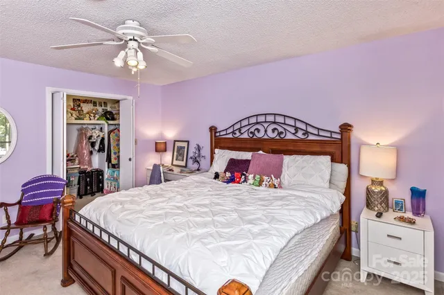 a bedroom with a bed a chandelier and dresser