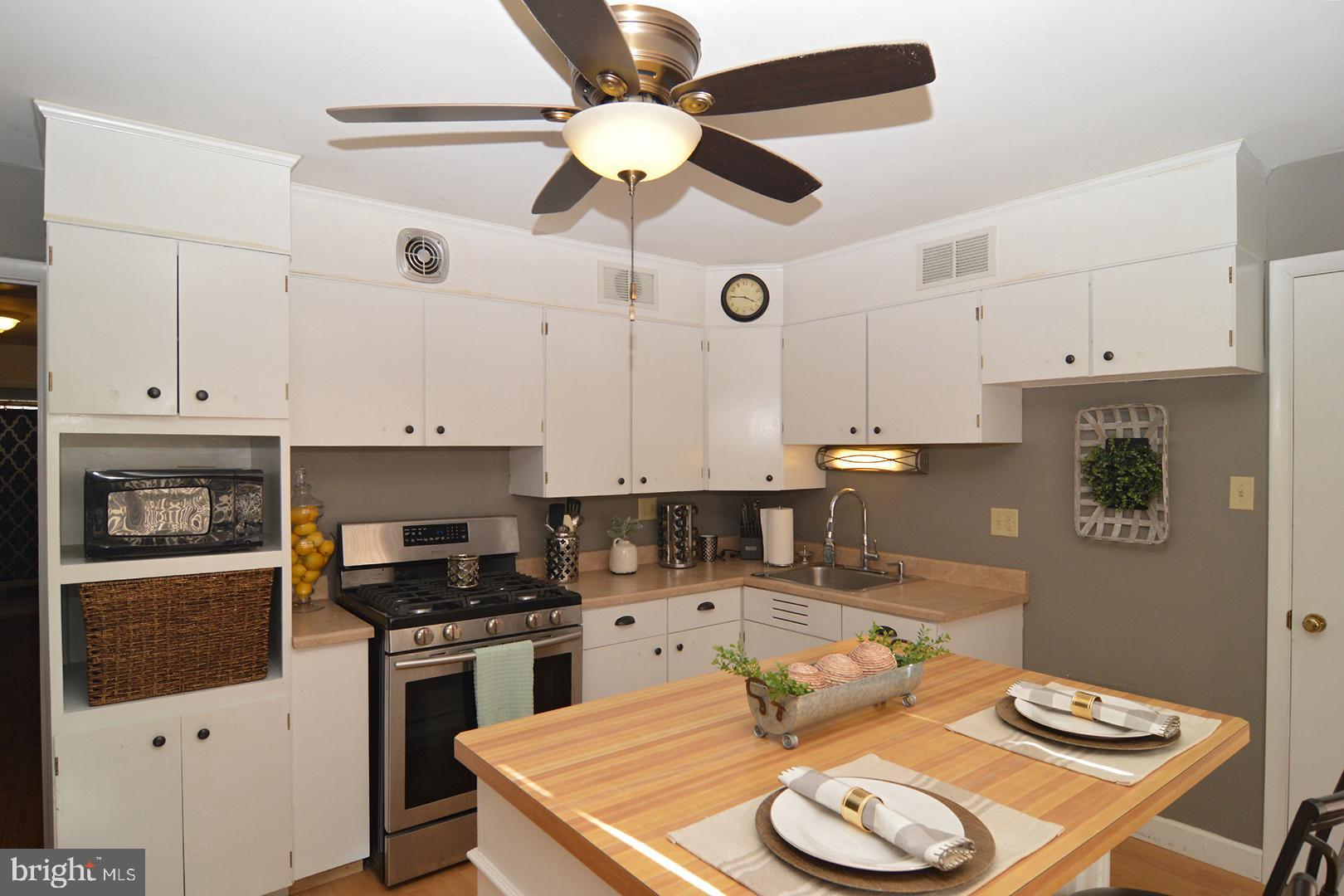 a kitchen with stainless steel appliances granite countertop a sink a stove and white cabinets