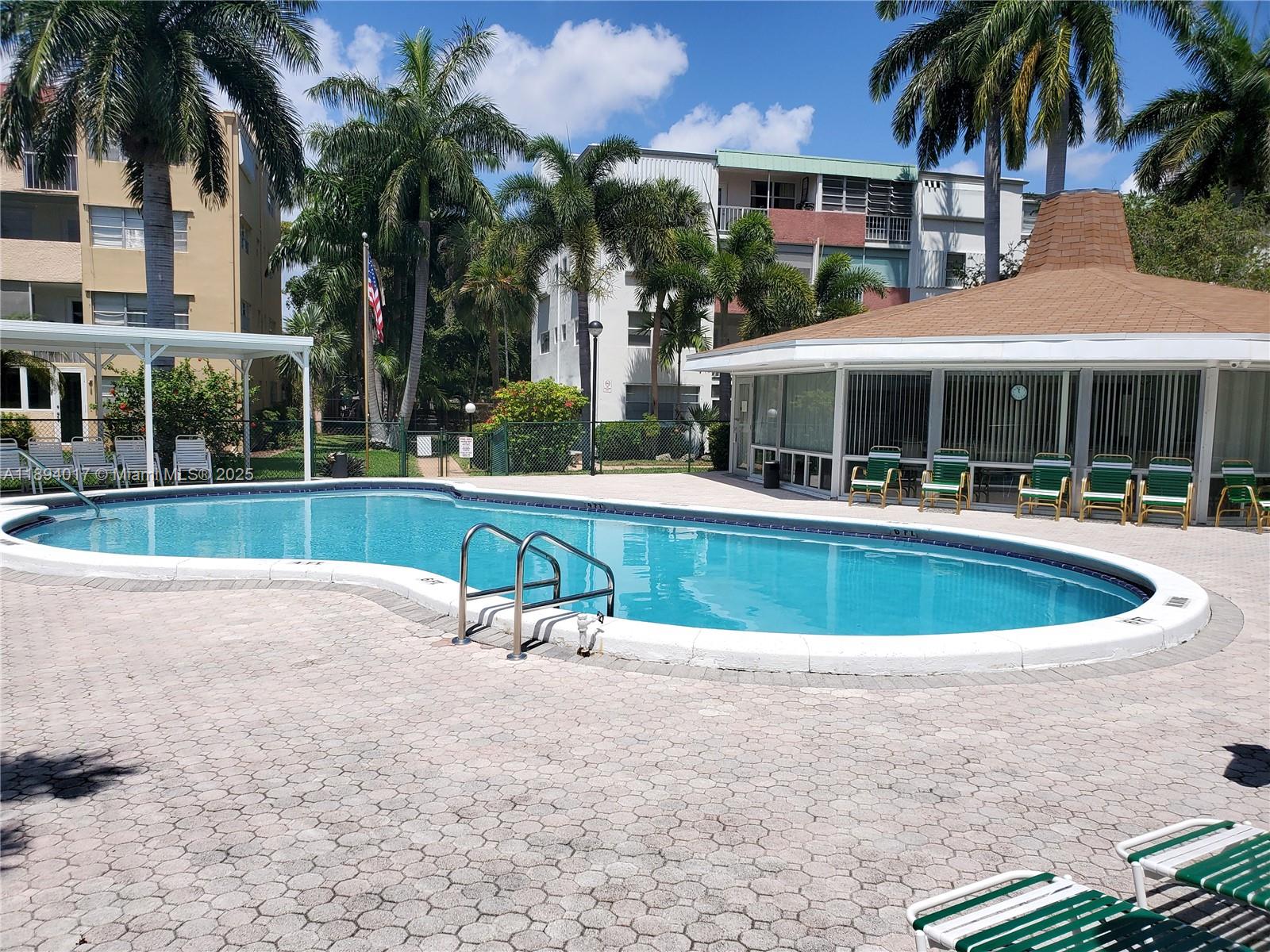 a view of a swimming pool with lawn chairs and palm trees
