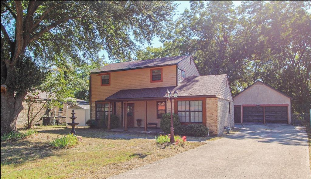 View of front of home with an outbuilding, a front yard, a patio area, roof with shingles, and a detached garage