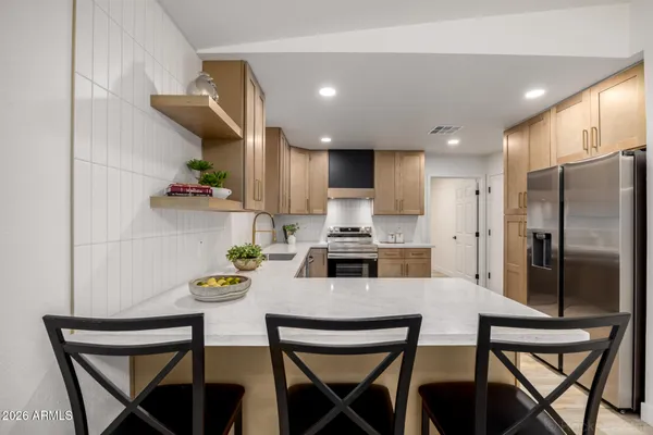 a kitchen with stainless steel appliances a dining table chairs and refrigerator