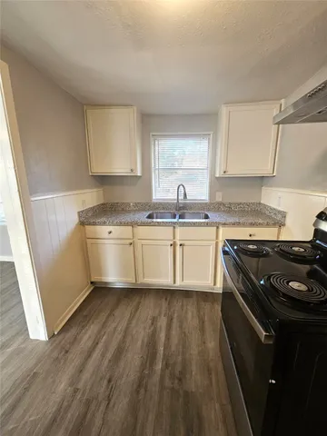 a kitchen with a sink a stove top oven and cabinetry