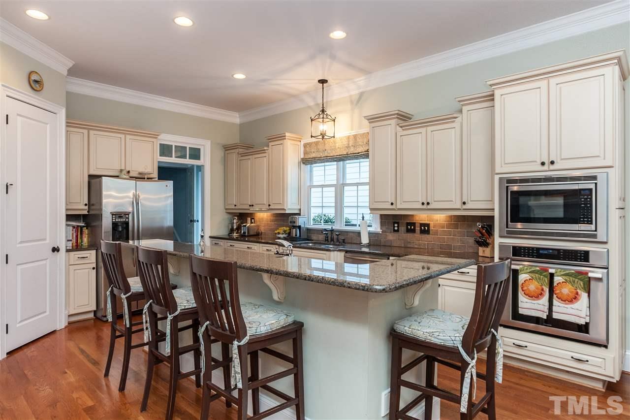 3105 Raymond Street Raleigh, NC 27607 - Photo 8 of 22 a kitchen with stainless steel appliances granite countertop a stove a refrigerator a microwave a dining table and chairs with wooden floor