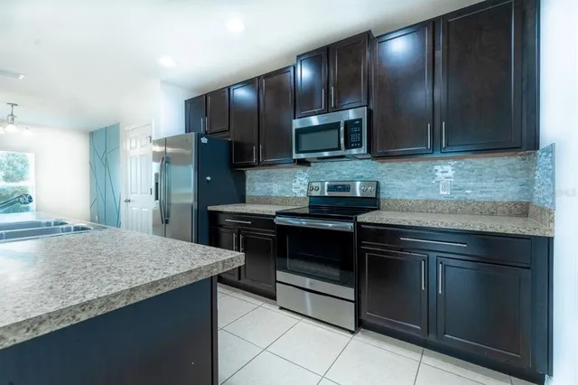 a kitchen with stainless steel appliances granite countertop wooden cabinets a refrigerator and a sink