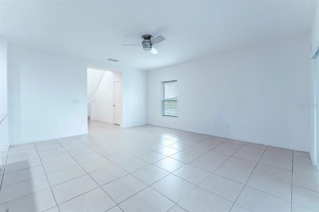 an empty room with a ceiling fan and carpet