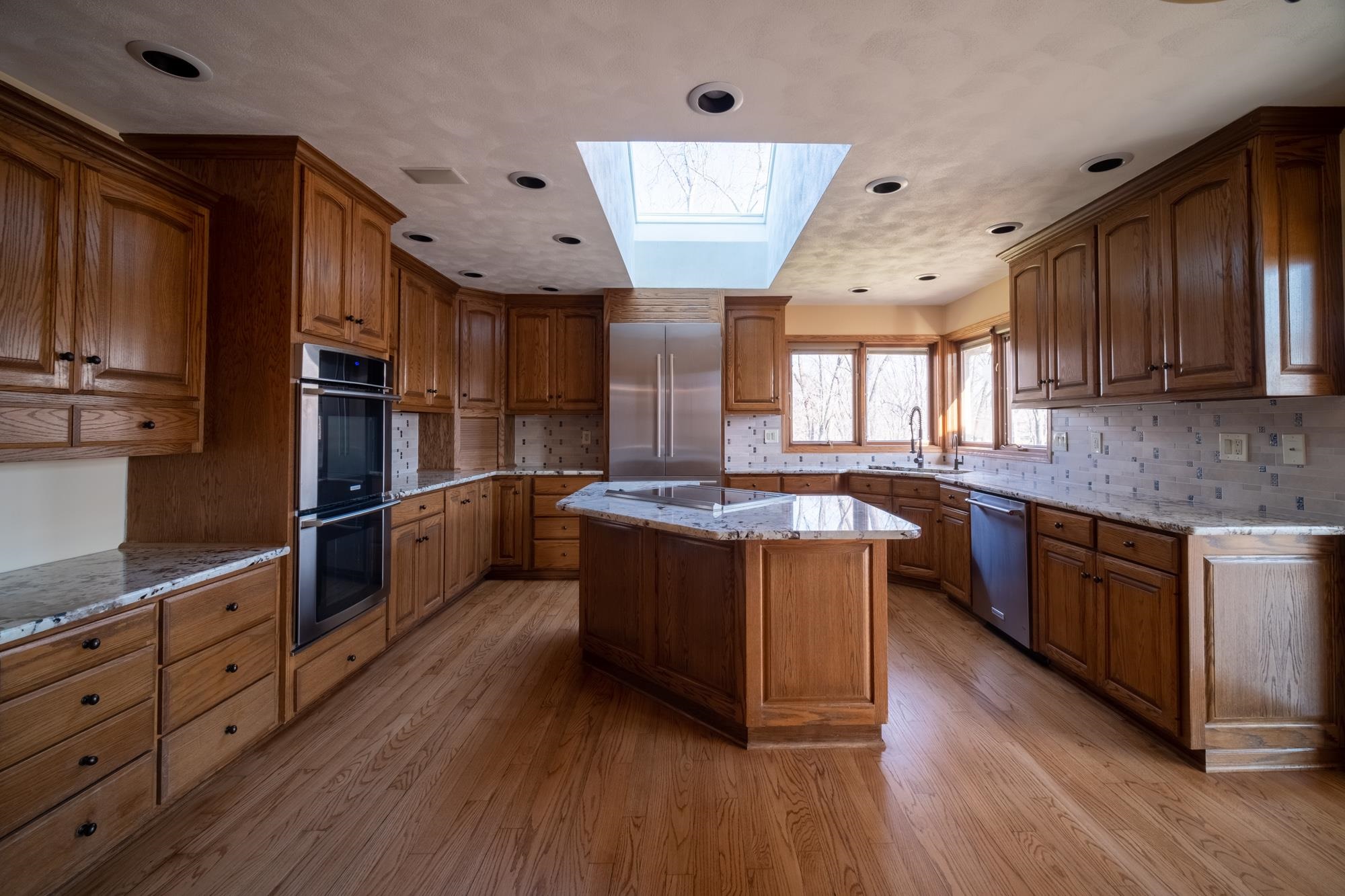 9805 Rivers Bend Drive Roscoe, IL 61073 - Photo 11 of 49 a large kitchen with stainless steel appliances wooden floors and wooden cabinets