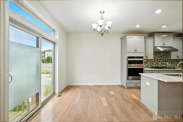 a kitchen with stainless steel appliances a stove top oven a chimney cabinets and wooden floor