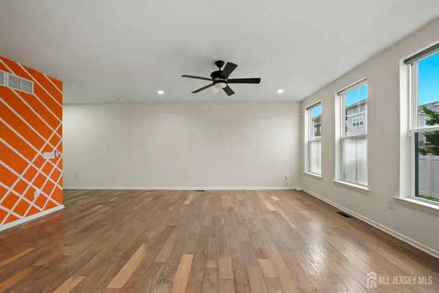 an empty room with windows and ceiling fan