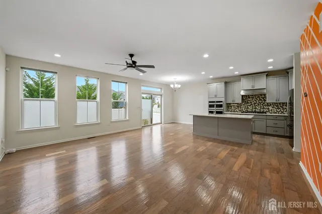 a view of an empty room with wooden floor and a kitchen
