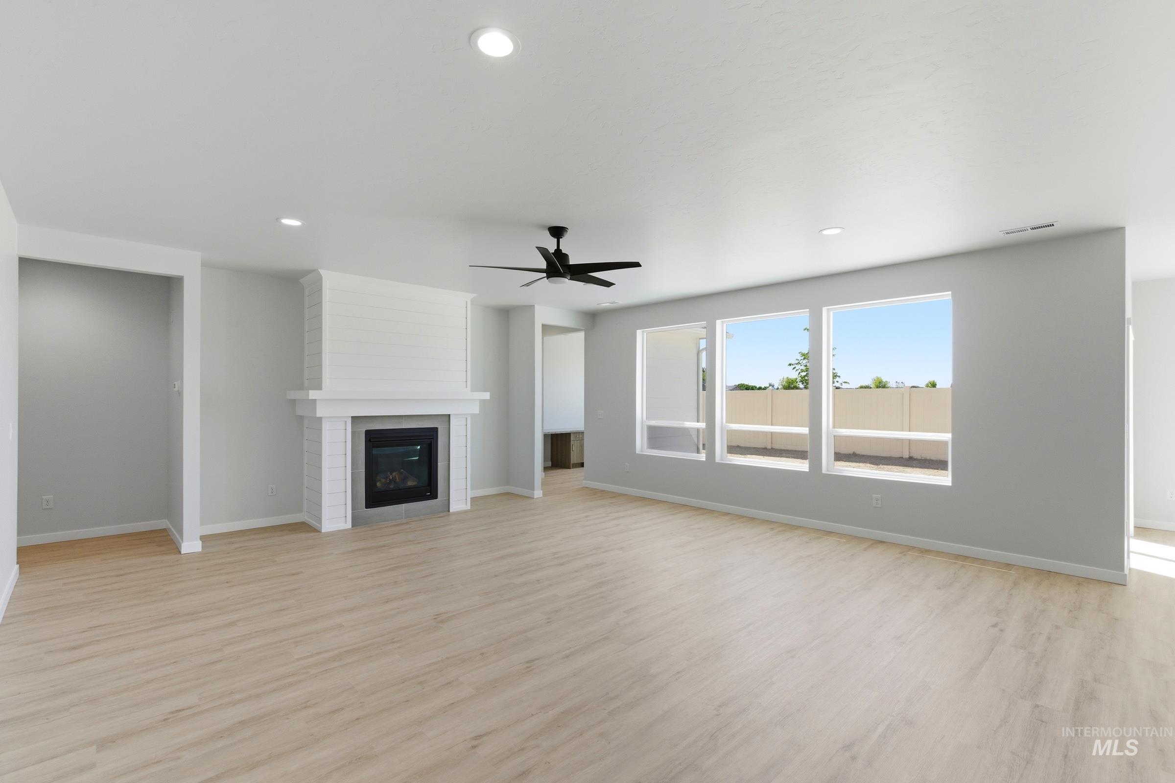13663 Redway Court Caldwell, ID 83607 - Photo 14 of 32 Expansive living area featuring light wood-finish flooring, a contemporary fireplace with a shiplap accent wall, a modern black ceiling fan, and recessed lighting