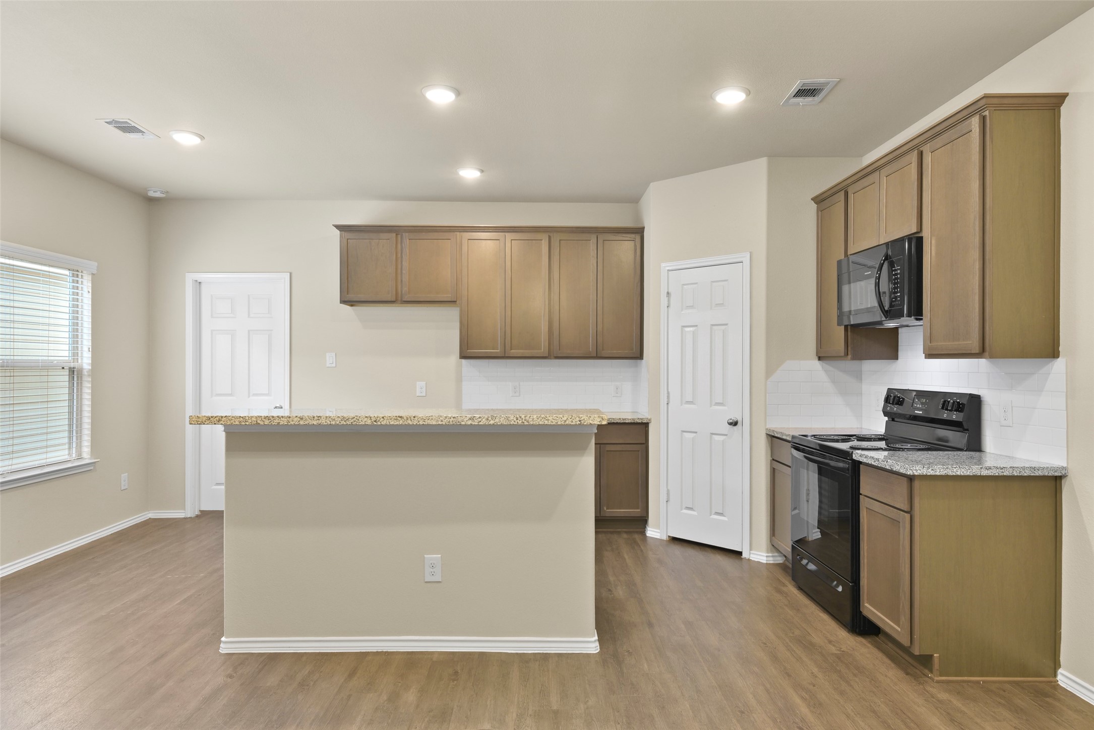 9650 Warm Spring Willis, TX 77318 - Photo 7 of 26 a kitchen with stainless steel appliances granite countertop a stove top oven a sink dishwasher and a refrigerator with wooden floor