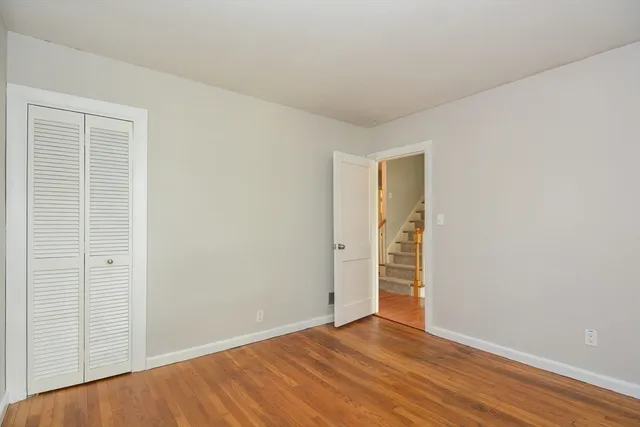 a view of an empty room with wooden floor and closet