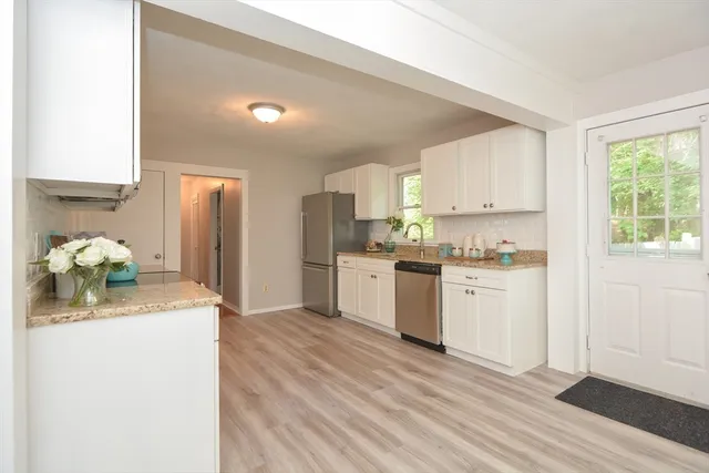 a kitchen with a refrigerator sink cabinets and wooden floor