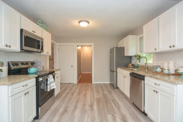 a kitchen with stainless steel appliances granite countertop a stove top oven a sink dishwasher and a refrigerator with wooden floor