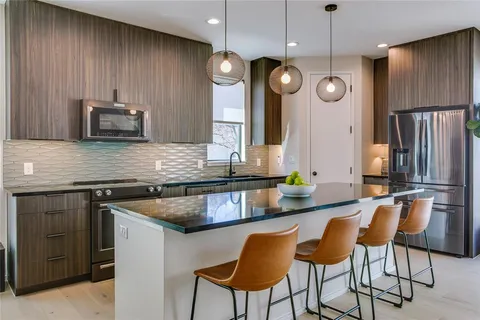 a kitchen with stainless steel appliances granite countertop wooden cabinets a stove a sink and a microwave
