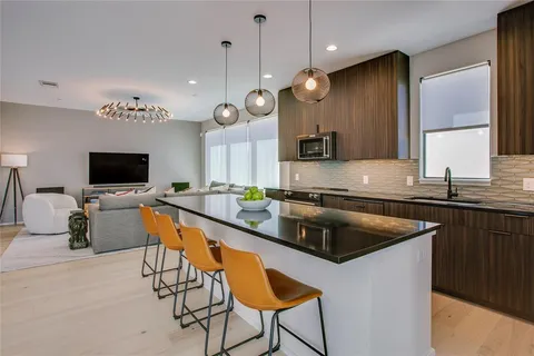 a kitchen with stainless steel appliances granite countertop a sink a stove a refrigerator a kitchen island with chairs and white cabinets