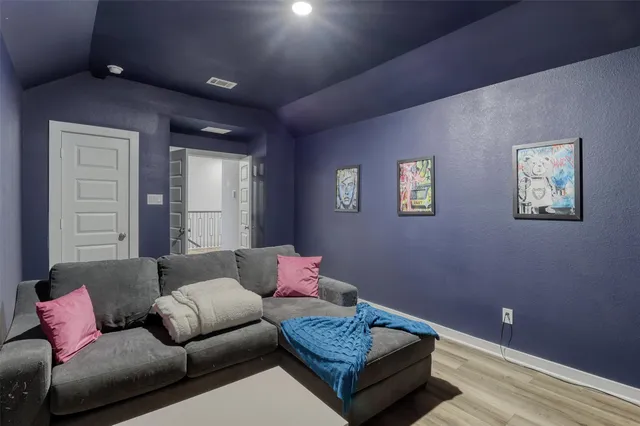 a view of a hallway to a livingroom with wooden floor and furniture