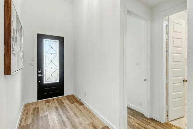 a view of a hallway with wooden floor and front door