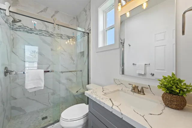 a bathroom with a granite countertop sink a toilet and shower